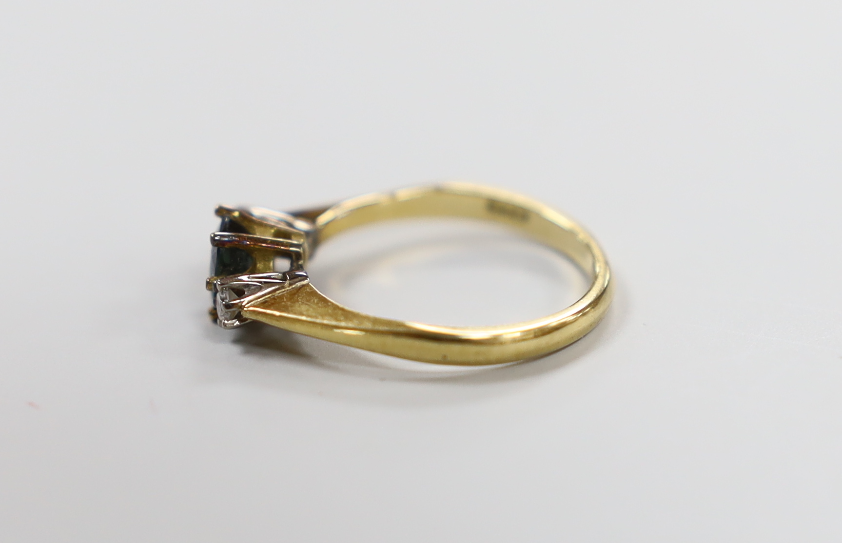 A modern 18ct gold, sapphire and diamond set three stone ring, size L, gross weight 2.7 grams.